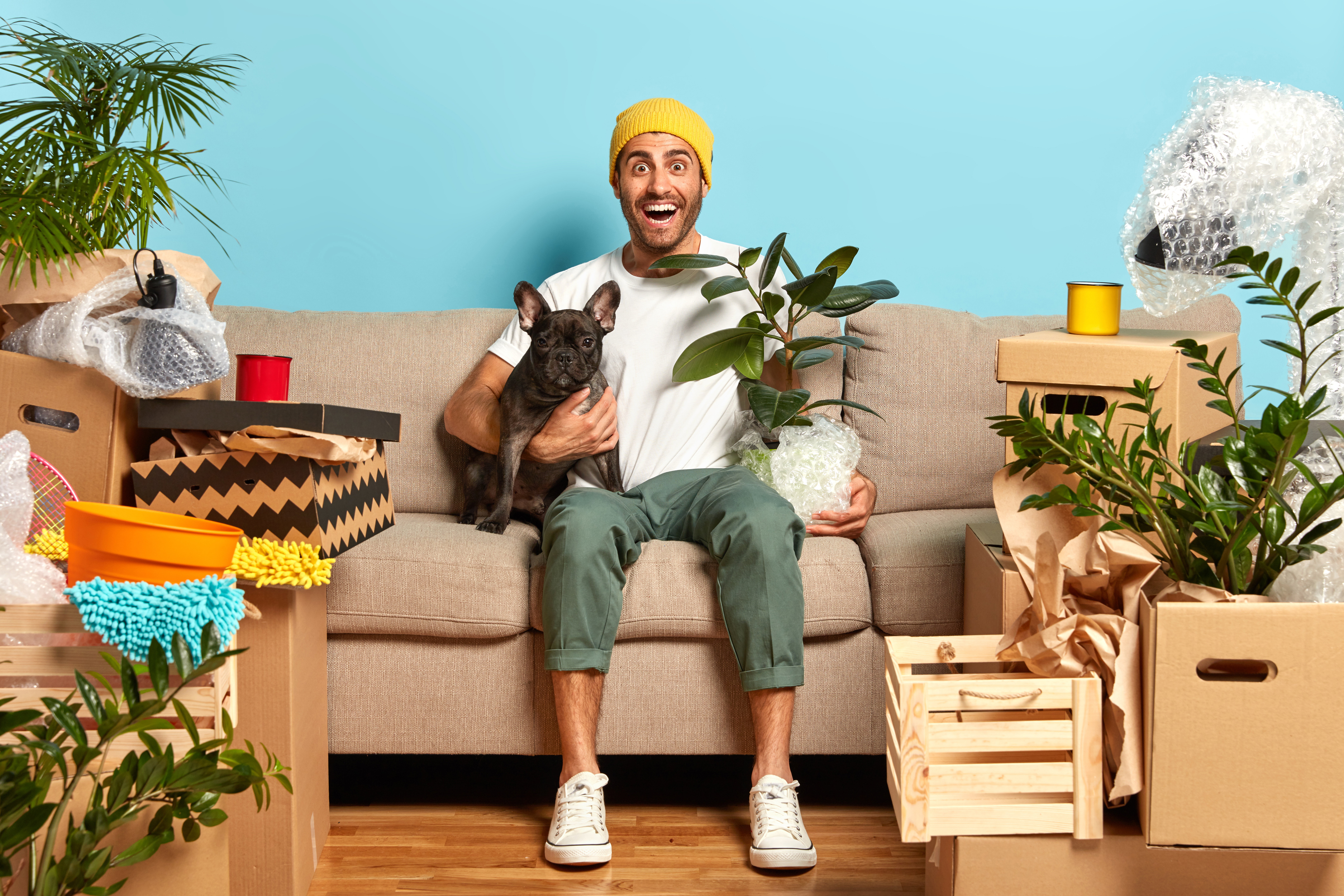 A man with his pet, sitting on a sofa with packed boxes.