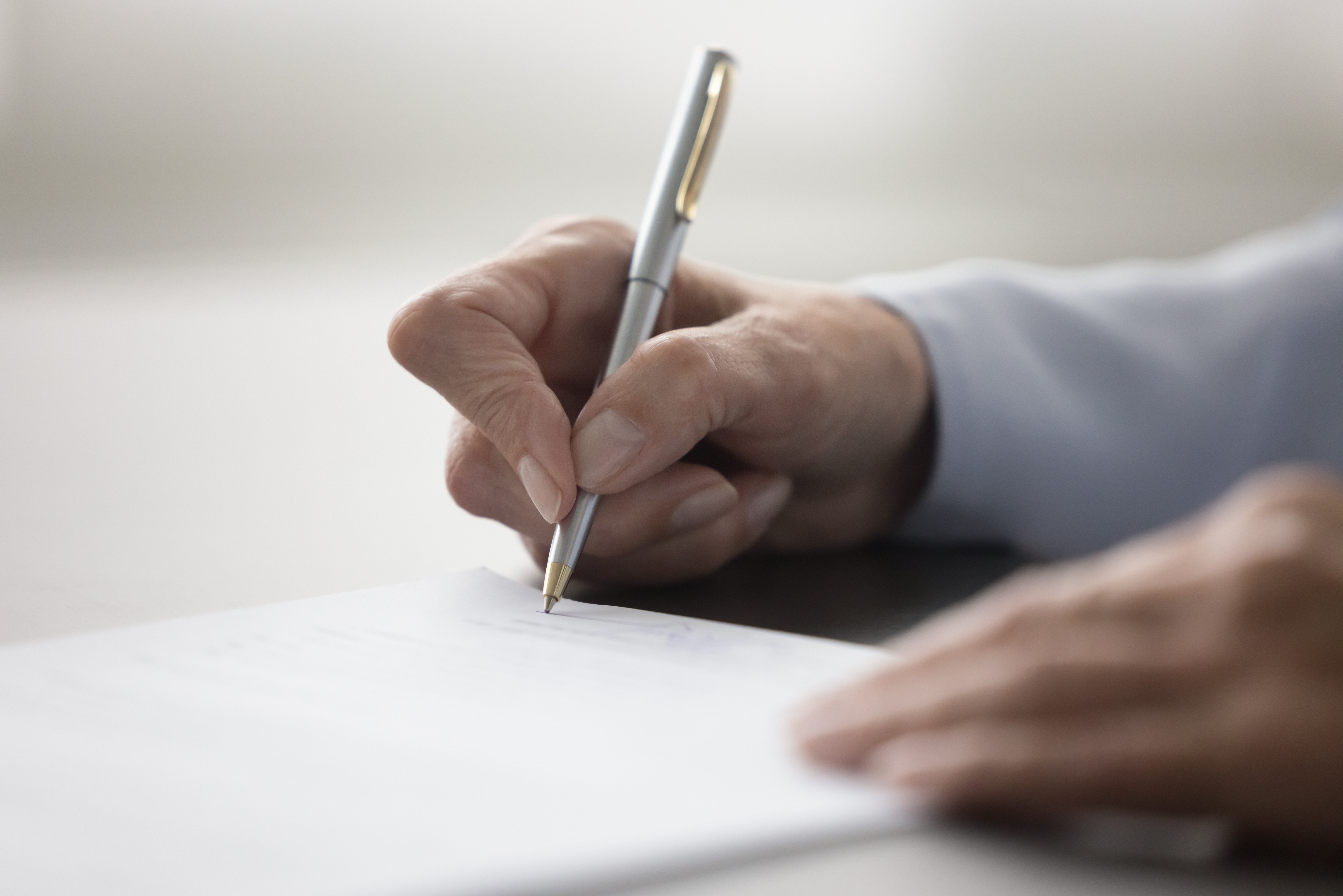An image of a person holding a pen and writing.