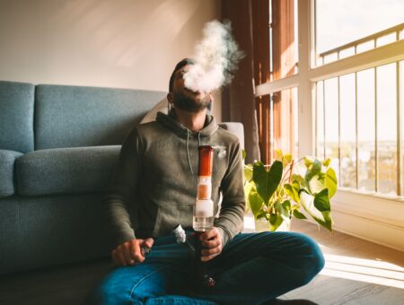 An image of a man smoking weed in an apartment.